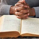 High angle shot of an unrecognizable man reading his bible while sitting outside