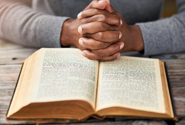 High angle shot of an unrecognizable man reading his bible while sitting outside