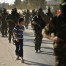 A Palestinian boy looks at Hamas militants as they take part in a protest against peace talks between Israel and the Palestinians, in central Gaza Strip September 20, 2013.   REUTERS/Mohammed Salem (GAZA - Tags: POLITICS CIVIL UNREST)