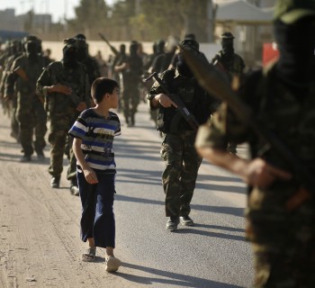 A Palestinian boy looks at Hamas militants as they take part in a protest against peace talks between Israel and the Palestinians, in central Gaza Strip September 20, 2013.   REUTERS/Mohammed Salem (GAZA - Tags: POLITICS CIVIL UNREST)