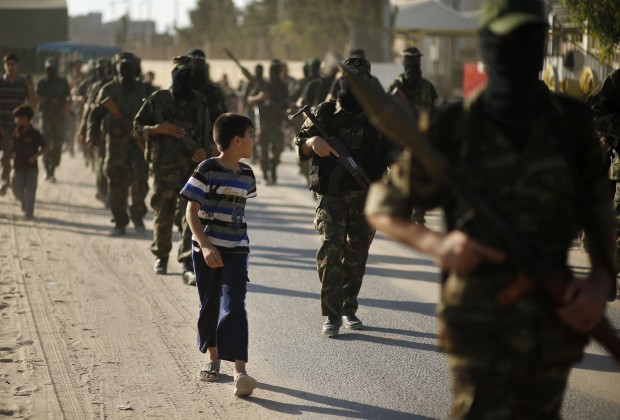 A Palestinian boy looks at Hamas militants as they take part in a protest against peace talks between Israel and the Palestinians, in central Gaza Strip September 20, 2013.   REUTERS/Mohammed Salem (GAZA - Tags: POLITICS CIVIL UNREST)