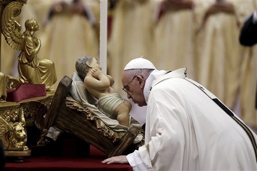 Pope Francis kisses a statue of Baby Jesus as he celebrates the Christmas Eve Mass in St. Peter's Basilica at the Vatican, Thursday, Dec. 24, 2015. (AP Photo/Gregorio Borgia)