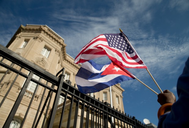 Edwardo Clark, a Cuban-American, holds an American flag and a Cuban flag as he celebrates outside the new Cuban embassy in Washington, Monday, July 20, 2015. The United States and Cuba restored full diplomatic relations Monday after more than five decades of frosty relations rooted in the Cold War. (AP Photo/Andrew Harnik)