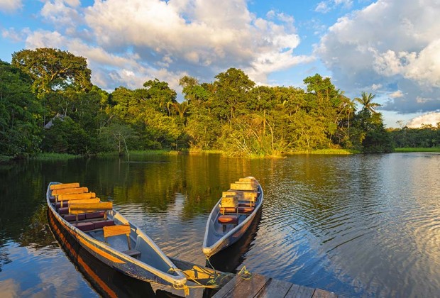 Two traditional wooden canoes at sunset in the Amazon River Basi