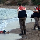 ADDS IDENTIFICATION OF CHILD   Paramilitary police officers investigate the scene before carrying the lifeless body of Aylan Kurdi, 3, after a number of migrants died and a smaller number were reported missing after boats carrying them to the Greek island of Kos capsized, near the Turkish resort of Bodrum early Wednesday, Sept. 2, 2015. The family — Abdullah, his wife Rehan and their two boys, 3-year-old Aylan and 5-year-old Galip — embarked on the perilous boat journey only after their bid to move to Canada was rejected. The tides also washed up the bodies of Rehan and Galip on Turkey's Bodrum peninsula Wednesday, Abdullah survived the tragedy. AP