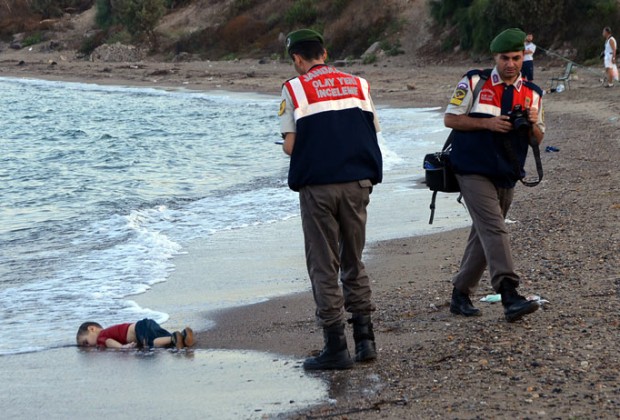 ADDS IDENTIFICATION OF CHILD   Paramilitary police officers investigate the scene before carrying the lifeless body of Aylan Kurdi, 3, after a number of migrants died and a smaller number were reported missing after boats carrying them to the Greek island of Kos capsized, near the Turkish resort of Bodrum early Wednesday, Sept. 2, 2015. The family — Abdullah, his wife Rehan and their two boys, 3-year-old Aylan and 5-year-old Galip — embarked on the perilous boat journey only after their bid to move to Canada was rejected. The tides also washed up the bodies of Rehan and Galip on Turkey's Bodrum peninsula Wednesday, Abdullah survived the tragedy. AP
