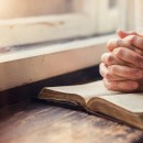 Hands of an unrecognizable woman with Bible praying