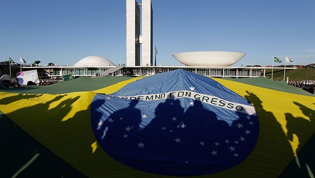 Demonstrators open a Brazil's flag in front of the National Congress during a protest in Brasilia, Brazil, Wednesday, June 26, 2013. The wave of protests that hit Brazil on June 17 began as opposition to transportation fare hikes, then expanded to a list of causes including anger at high taxes, poor services and high World Cup spending, before coalescing around the issue of rampant government corruption. (AP Photo/Eraldo Peres)