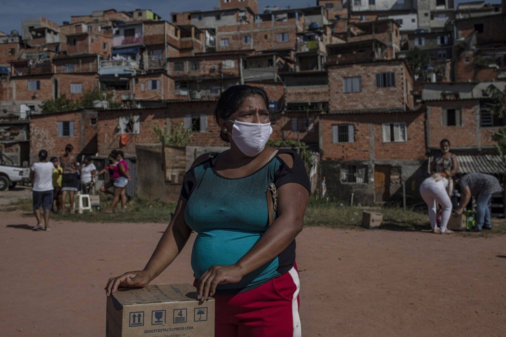 Moradora recebe uma cesta de alimentos e produtos de higiene doados na favela do Vale das Virtudes, São Paulo, 12 de junho de 2020. (Victor Moriyama/Bloomberg)