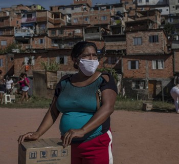 Moradora recebe uma cesta de alimentos e produtos de higiene doados na favela do Vale das Virtudes, São Paulo, 12 de junho de 2020. (Victor Moriyama/Bloomberg)