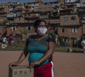 Moradora recebe uma cesta de alimentos e produtos de higiene doados na favela do Vale das Virtudes, São Paulo, 12 de junho de 2020. (Victor Moriyama/Bloomberg)