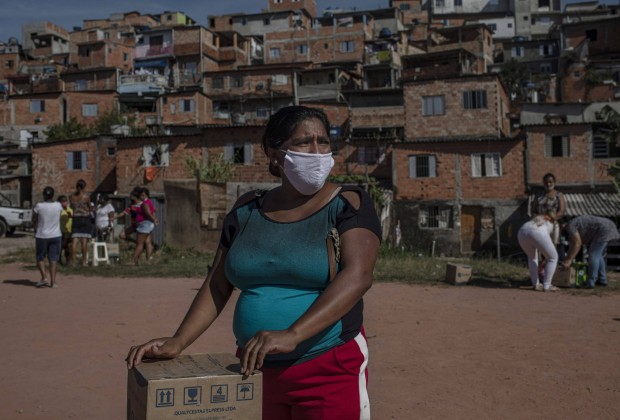 Moradora recebe uma cesta de alimentos e produtos de higiene doados na favela do Vale das Virtudes, São Paulo, 12 de junho de 2020. (Victor Moriyama/Bloomberg)