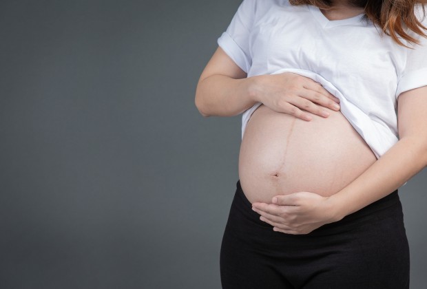 A beautiful pregnant woman on a gray background.