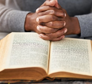 High angle shot of an unrecognizable man reading his bible while sitting outside