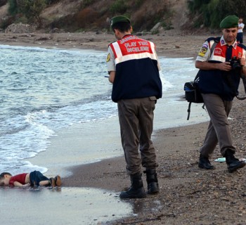 ADDS IDENTIFICATION OF CHILD   Paramilitary police officers investigate the scene before carrying the lifeless body of Aylan Kurdi, 3, after a number of migrants died and a smaller number were reported missing after boats carrying them to the Greek island of Kos capsized, near the Turkish resort of Bodrum early Wednesday, Sept. 2, 2015. The family — Abdullah, his wife Rehan and their two boys, 3-year-old Aylan and 5-year-old Galip — embarked on the perilous boat journey only after their bid to move to Canada was rejected. The tides also washed up the bodies of Rehan and Galip on Turkey's Bodrum peninsula Wednesday, Abdullah survived the tragedy. AP