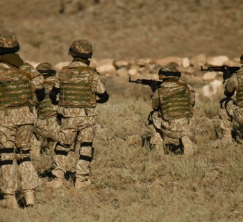 A shot of Armenian military soldiers training in a dry field
