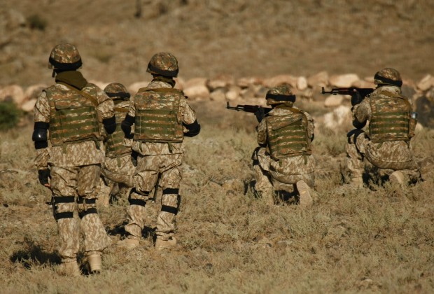 A shot of Armenian military soldiers training in a dry field