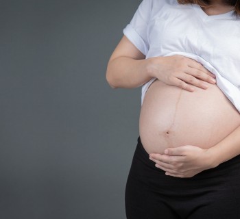 A beautiful pregnant woman on a gray background.